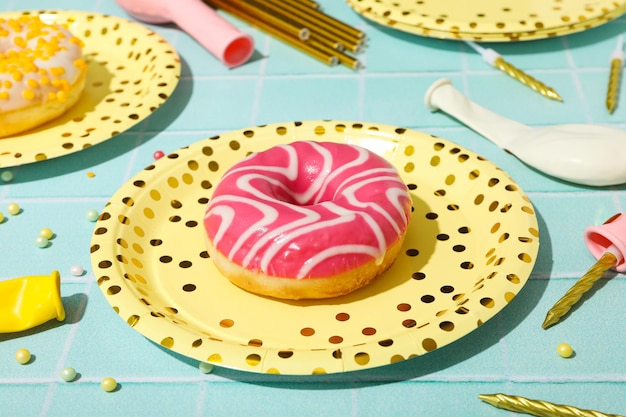 Donuts on plates balloons and candles on blue background