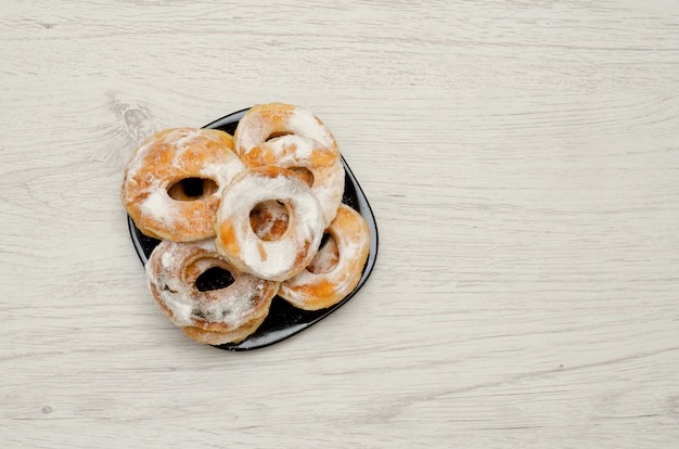 Donuts sprinkled with powdered sugar on a light wooden , with copyspace. top view