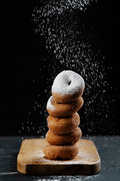 Donuts vormen een toren die glassuiker op zwarte achtergrond toepast