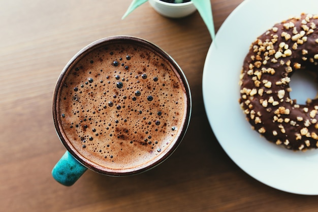 Ciambelle sul piatto bianco e caffè sul tavolo di legno.