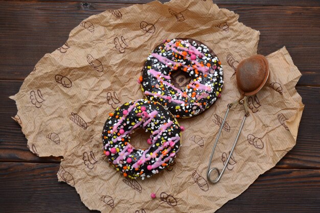 Donuts with bright sprinkles on parchment paper flat lay