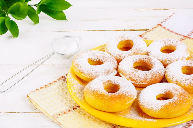 캐스터 설탕과 도넛은 노란색 접시에 제공