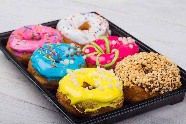 Donuts with glaze in a box on a white wooden background