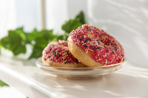 Donuts with icing on a plate in the sun.