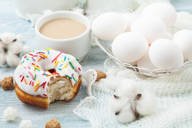 Donuts with icing on a white table, white eggs