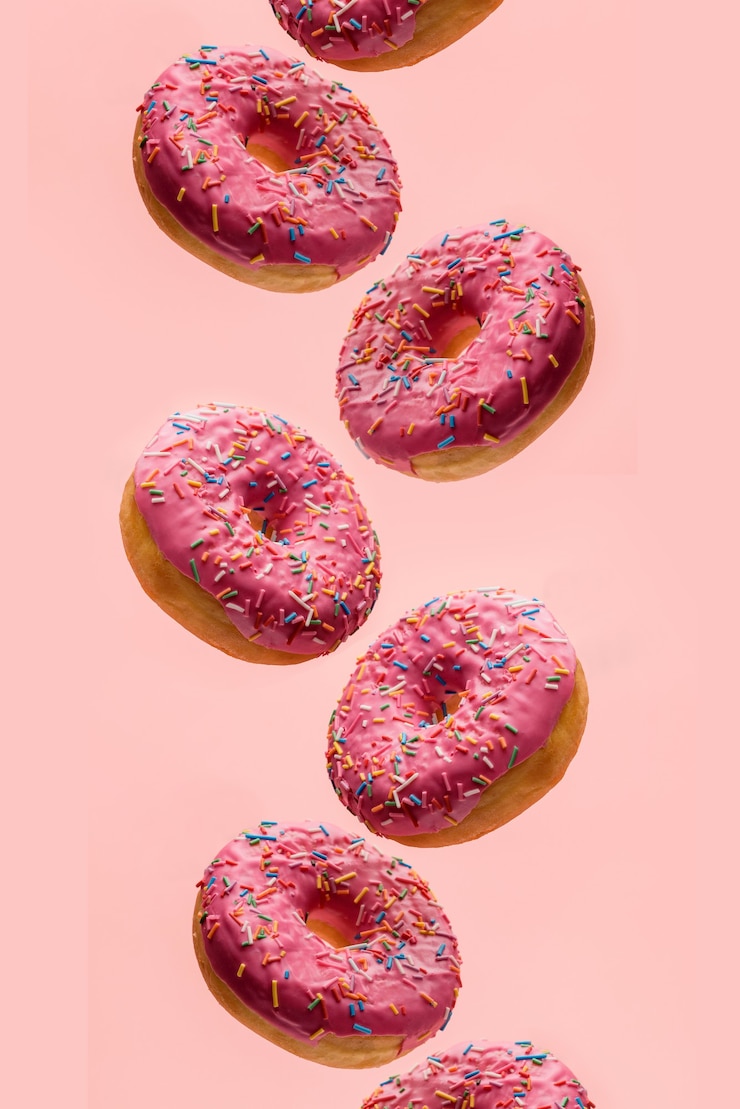Photo donuts with pink glaze on a pastel pink background.