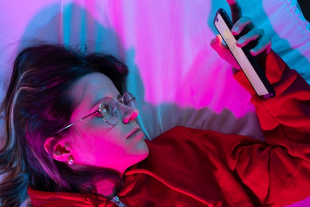 Doom scrolling on bed at night with neon lights technology at bed concept