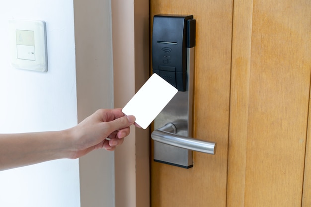 문 액세스 제어-여자가 손을 잡고 문을 잠그고 잠금을 해제하는 흰색 모형 키 카드. 디지털 도어록.