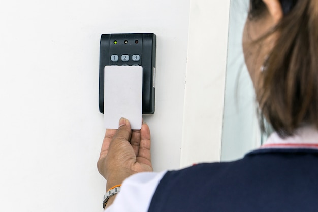 Door access control - young woman holding a key card to lock and unlock door.