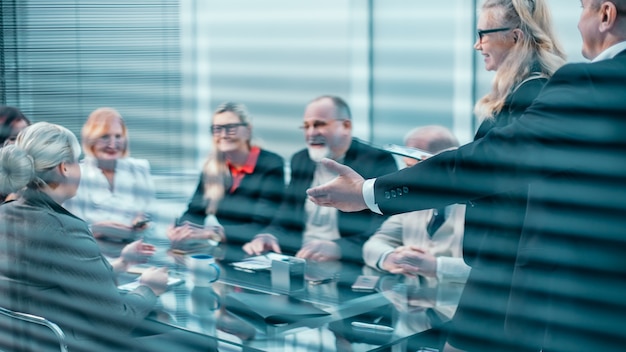 door de jaloezieën. een groep werknemers applaudisseren op een zakelijke bijeenkomst. succes concept