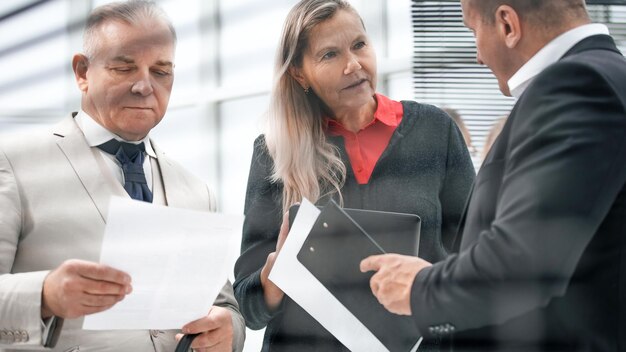 Door de jaloezieën. zakenmensen bespreken documenten die op kantoor staan