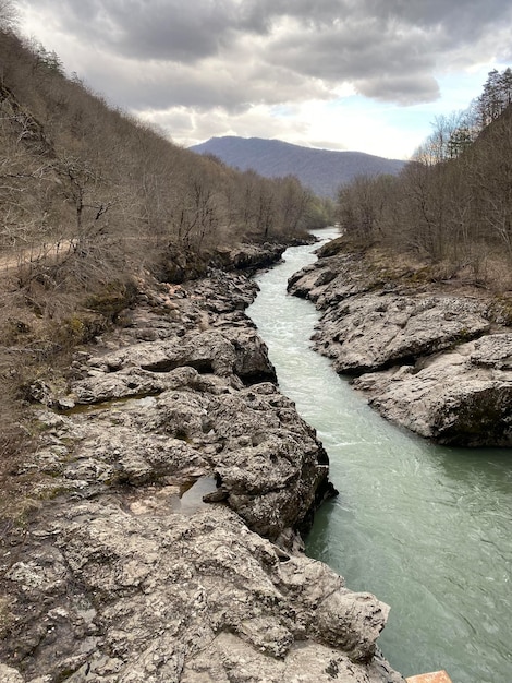 Door een rotsachtig landschap stroomt een rivier met daarboven een wolkenlucht.