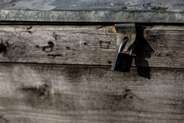 Door lock hangs on an old old wooden chest, hard shadows. wood\
texture.