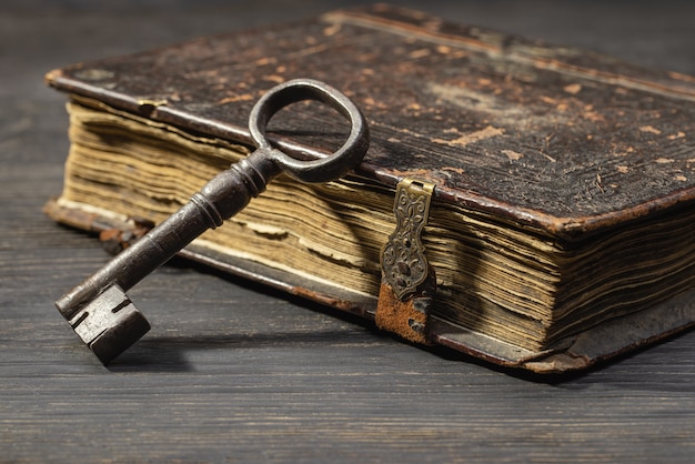 걸쇠에 있는 골동품 책 옆에 있는 오래된 금속 열쇠 어두운 탁자에 있는 복고풍 항목