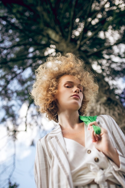 Doordachte blik. Curly haired jonge vrouw in een park op zoek attent