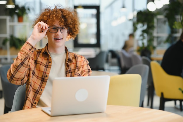 Doordachte freelancer in vrijetijdskleding die op laptop bladert terwijl hij overdag aan een project op het terras van een café werkt