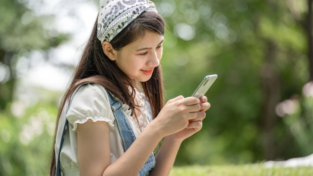 Doordachte glimlach vrouw in park met behulp van slimme telefoon Portret van een jonge charmante zakenvrouw check