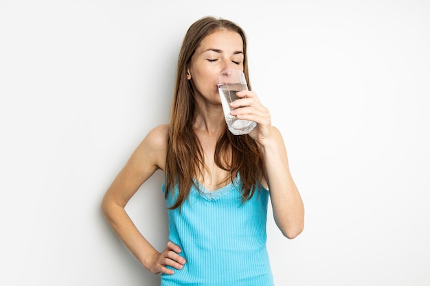 Doordachte jonge vrouw drinkwater uit een glas op witte achtergrond