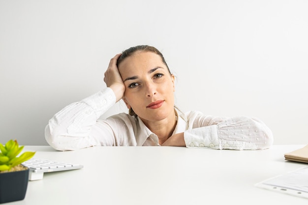 Doordachte jonge vrouw in shirt gluren van achter het bureaublad op kantoor