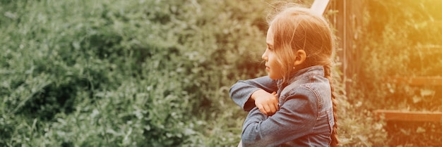 Doordachte openhartige achtjarige jongen staat op de trap met gras en geniet van de natuur prepuberale leeftijd van kinderen en leeft geest psychologie en geestelijke gezondheid concept banner mockup flare