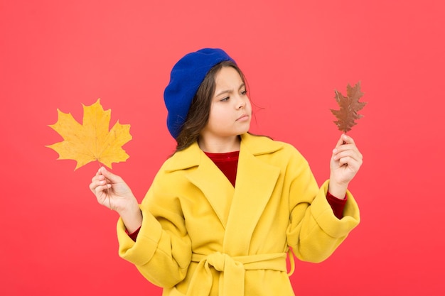 Doordachte schoonheid herfst kind mode nadenkend meisje met esdoornblad herfst seizoen gevallen bladeren bos parijse meisje kind in franse baret en gele jas schooltijd jeugd geluk