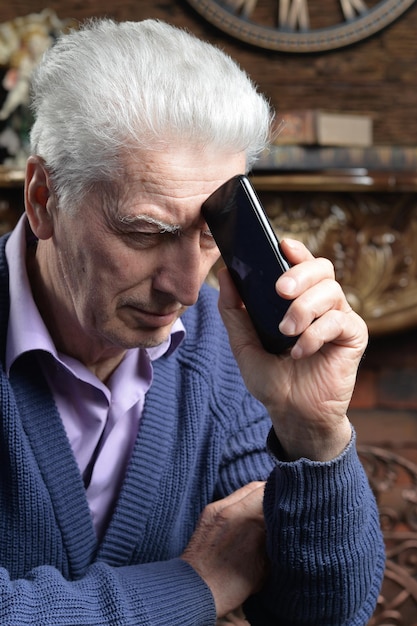 Doordachte senior man met smartphone