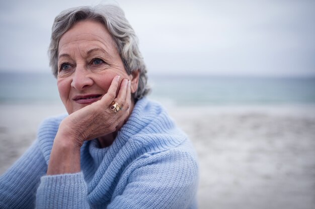 Doordachte senior man zittend op het strand