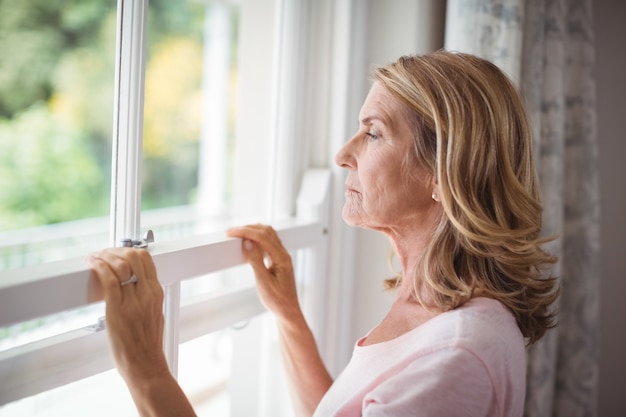 Doordachte senior vrouw kijkt uit het raam