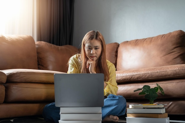 Doordachte serieuze indiase vrouw die aan laptop werkt en thuis denkt aan het oplossen van online onderwijsproblemen