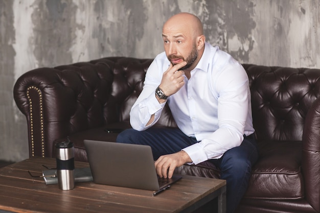 Doordachte volwassen man aan het werk op een computer in het kantoor