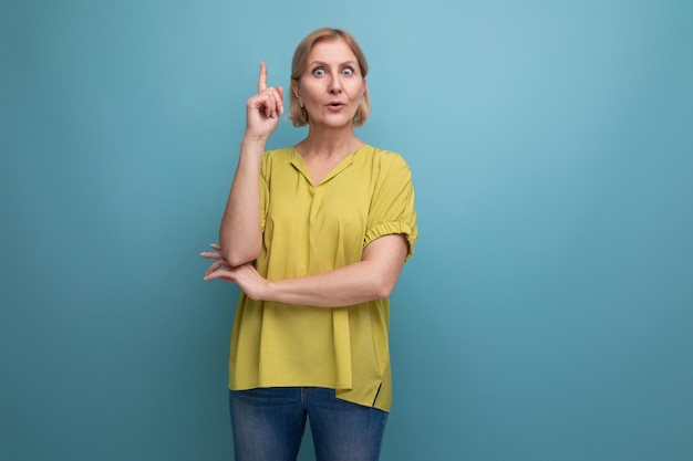 Doordachte volwassen vrouw toont kennis op blauwe achtergrond