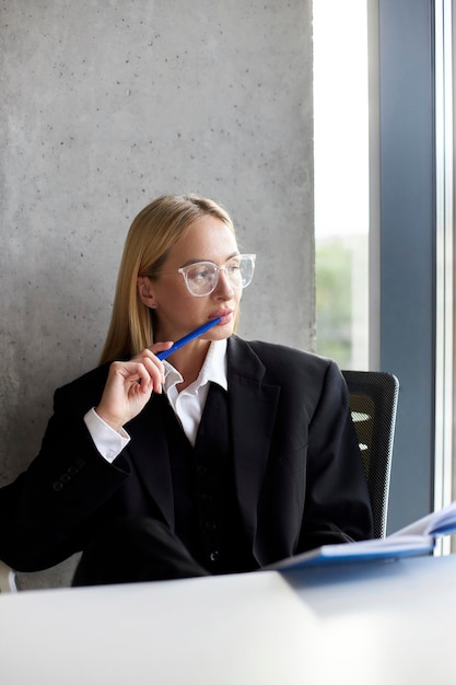 Doordachte vrouw die aan het bureau zit en aantekeningen maakt bij het lezen van een businessplan