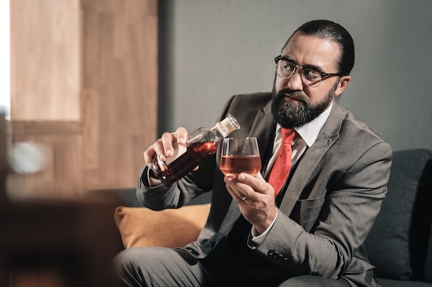 Doorgaan met drinken. Bebaarde man die lijdt aan zenuwinzinking en whisky blijft drinken