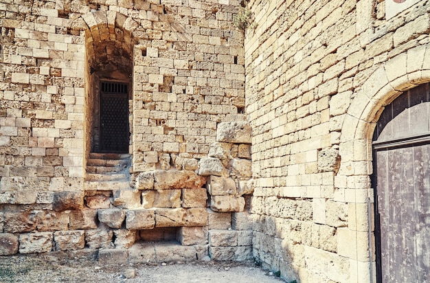 Doorstane oude de vestingsbaksteen en steenmuur van Rhodos met lege boogdeuropening