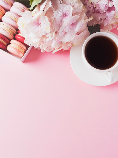 Doos met bitterkoekjes en kopje koffie, bloemen op roze