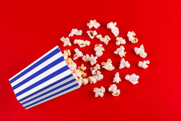 Foto doos met popcorn gestreept in verschillende kleuren op een rode achtergrond