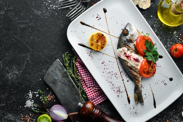 Foto pesce dorado alla griglia con salsa e verdure su un piatto vista dall'alto spazio di copia gratuito