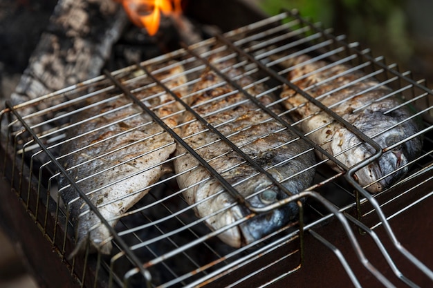 Dorado fish is fried on the grill. Picnic in nature. Close-up.