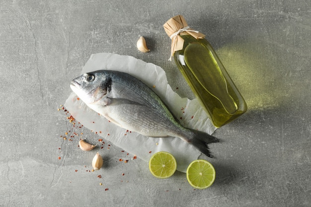 Dorado fish, oil and spices on grey background, top view