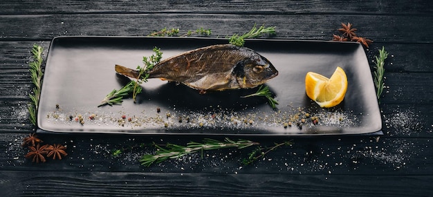 Dorado vis met in blokjes gesneden tomaten en groenten op een zwarte houten achtergrond Kopieer de ruimte