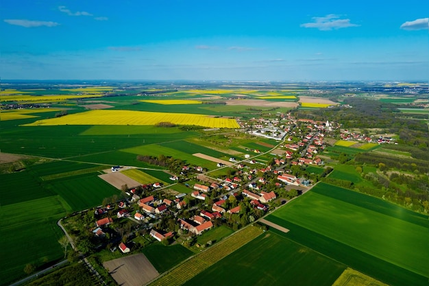 Dorp in de buurt van bloeiende koolzaadvelden in luchtfoto van het platteland