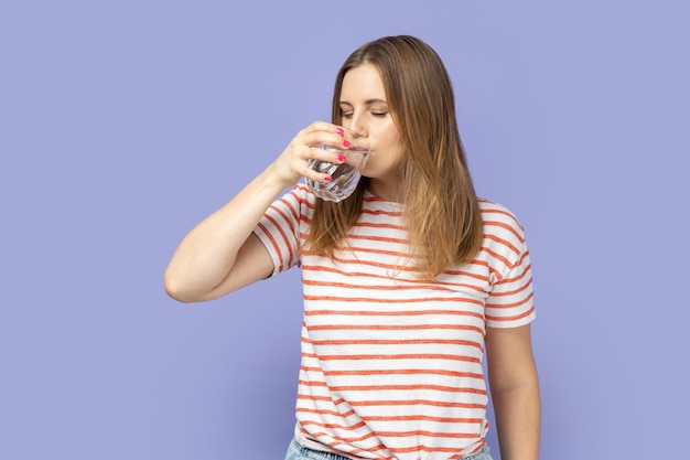 Dorstige aantrekkelijke mooie jonge volwassen blonde vrouw drinkwater uit glas gezond eten