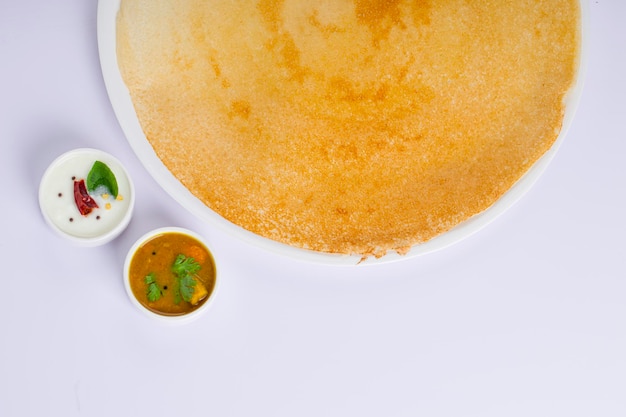 Dosa Ghee gebraden Dosaberoemd Zuid-Indiaas ontbijtproduct dat op traditionele wijze in gietijzeren pan is gemaakt en op een whiteplate met bijgerecht op een witte geïsoleerde achtergrond is gerangschikt