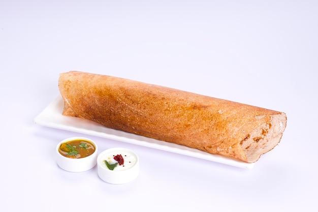 Dosa Ghee 로스트 Dosafamous 남부 인도식 아침 식사 항목은 전통적인 방식으로 철판으로 만들어지고 흰색 바탕에 흰색 바탕에 분리된 반찬이 배열되어 있습니다.