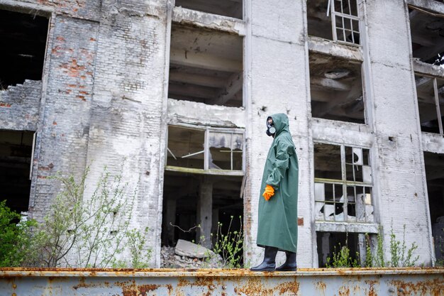 A dosimetrist scientist in protective clothing and a gas mask checks the level of radioactive radiation in the danger zone Environmental pollution disaster