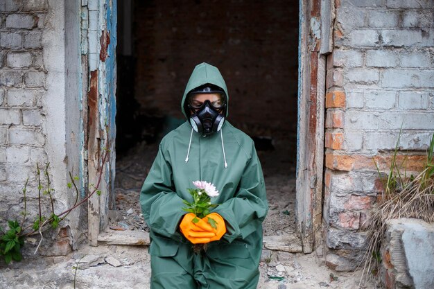 A dosimetrist scientist in protective clothing and a gas mask examines the danger zone closeup flower in hands