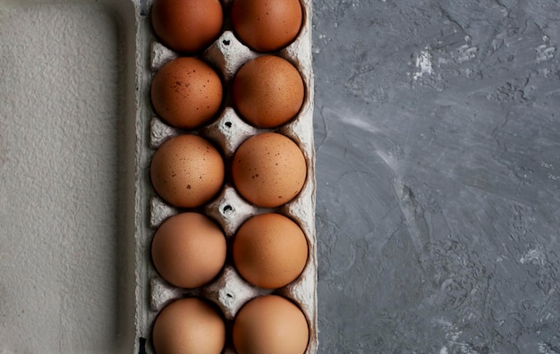 点線の茶色の卵は灰色のコンクリートのテーブルの上の紙袋に横たわっています