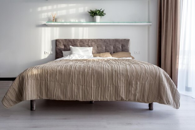 Double bed in interior of the modern bedroom in loft flat in light color style of expensive apartments