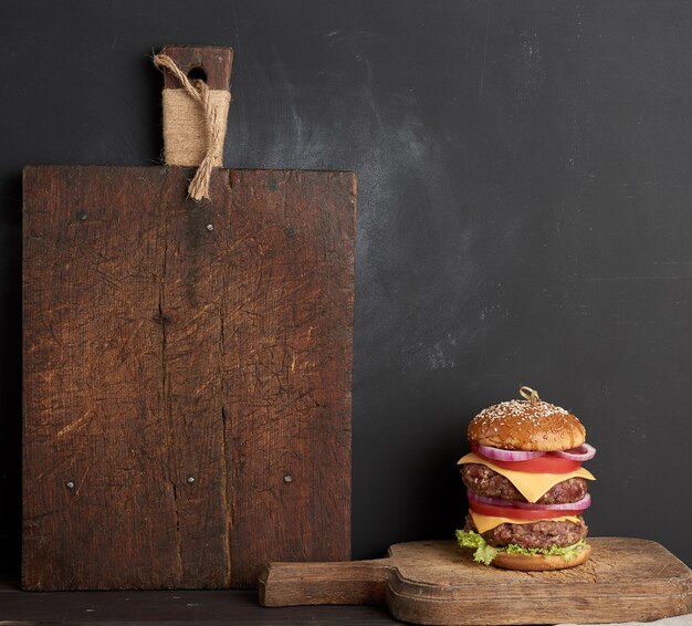 Double cheeseburger with tomatoes, onions, barbecue cutlet and sesame bun