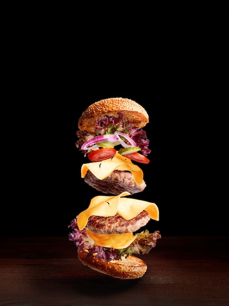 Double cheeseburger on a wooden surface with a dark background and space for text